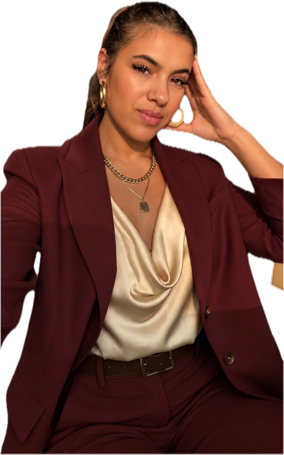 Patrícia com blazer vinho e blusa creme, com a mão apoiada na cabeça